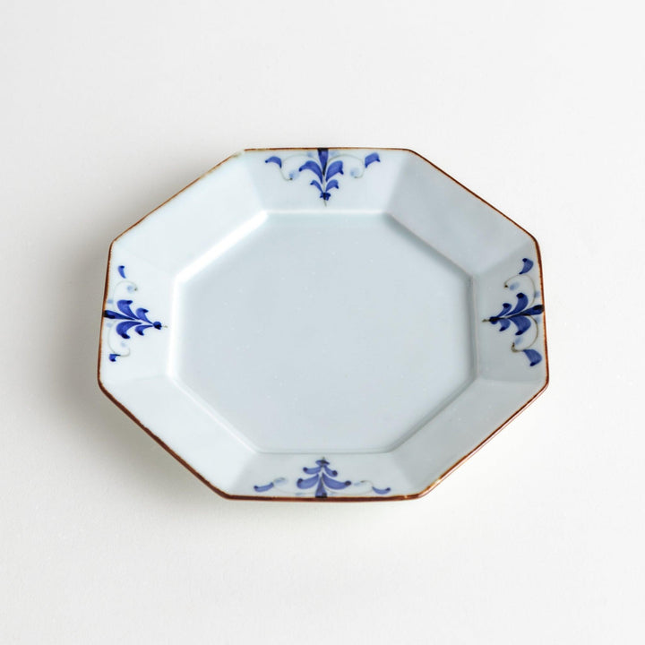 Octagonal white porcelain dessert plate with a blue floral motif and brown accent trim.