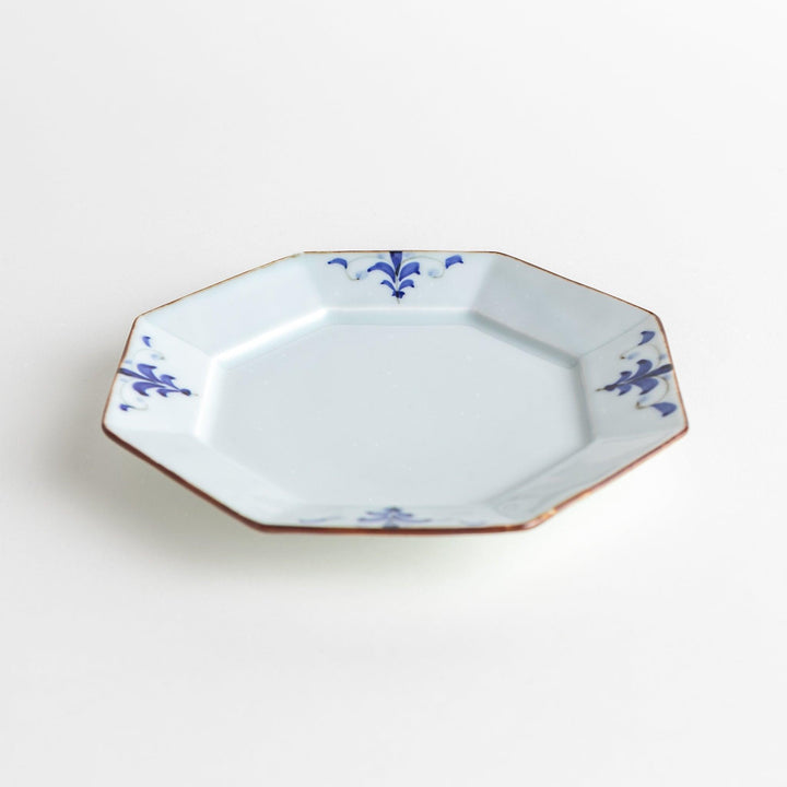 Octagonal white porcelain dessert plate with a blue floral motif and brown accent trim.