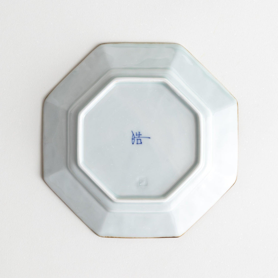 Octagonal white porcelain dessert plate with a blue floral motif and brown accent trim.