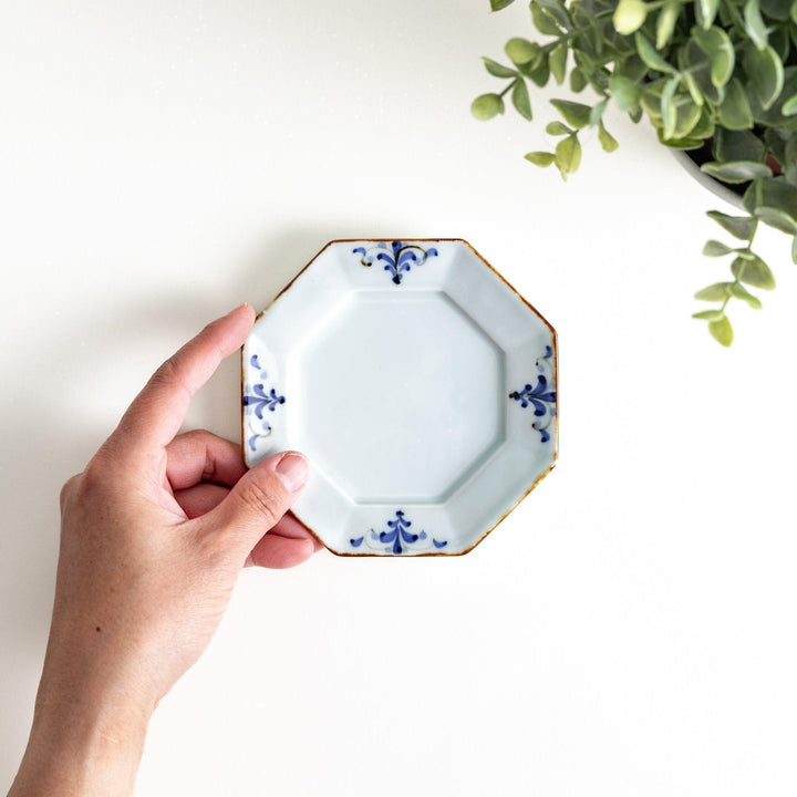 Octagonal white porcelain sauce dish with a blue floral motif and brown accent trim.