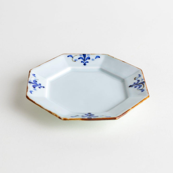 Octagonal white porcelain sauce dish with a blue floral motif and brown accent trim.
