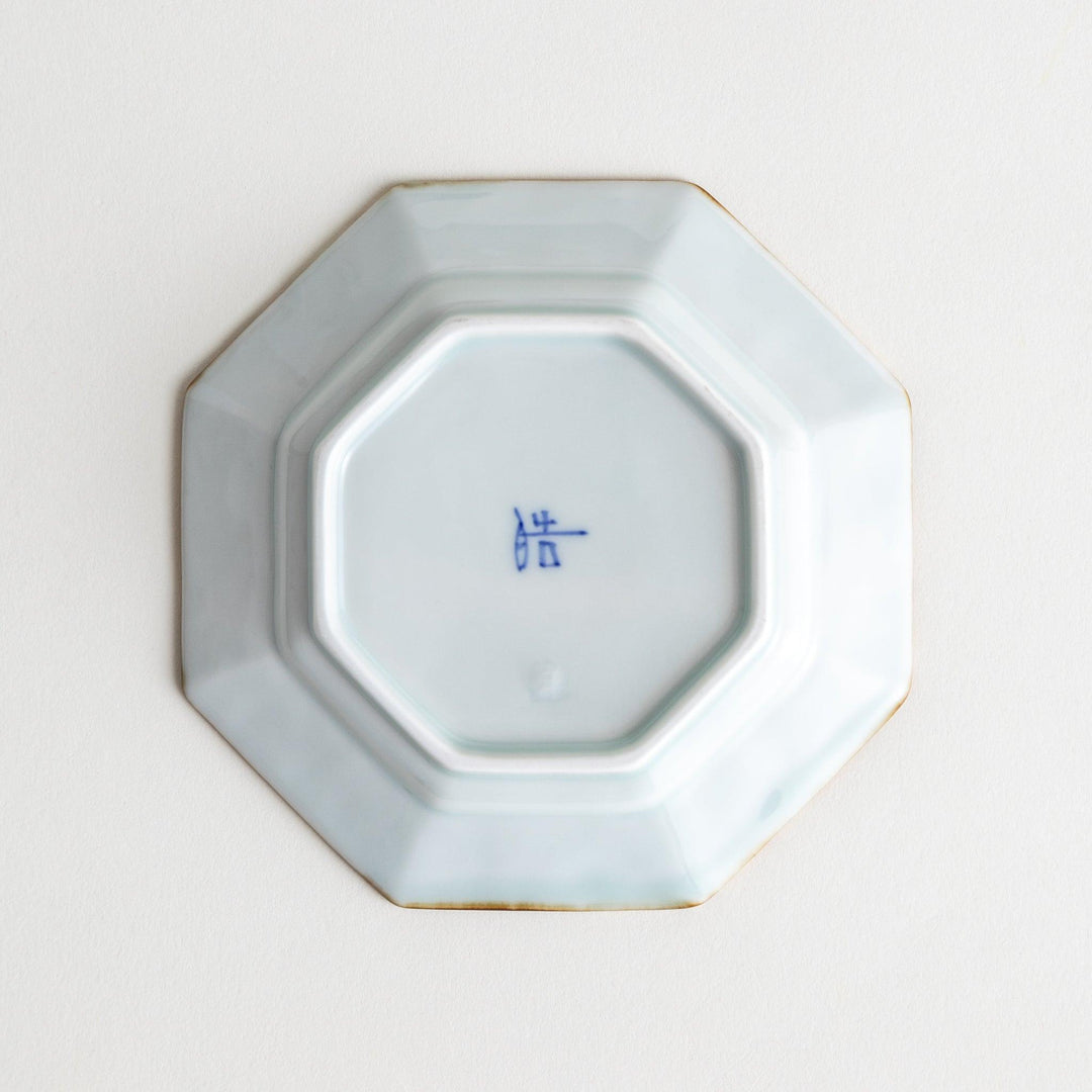 Octagonal white porcelain dessert plate with a blue floral motif and brown accent trim.