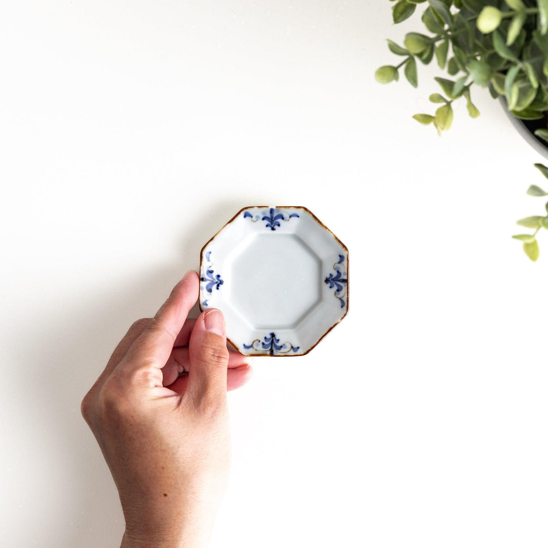 Octagonal white porcelain small sauce dish with a blue floral motif and brown accent trim.