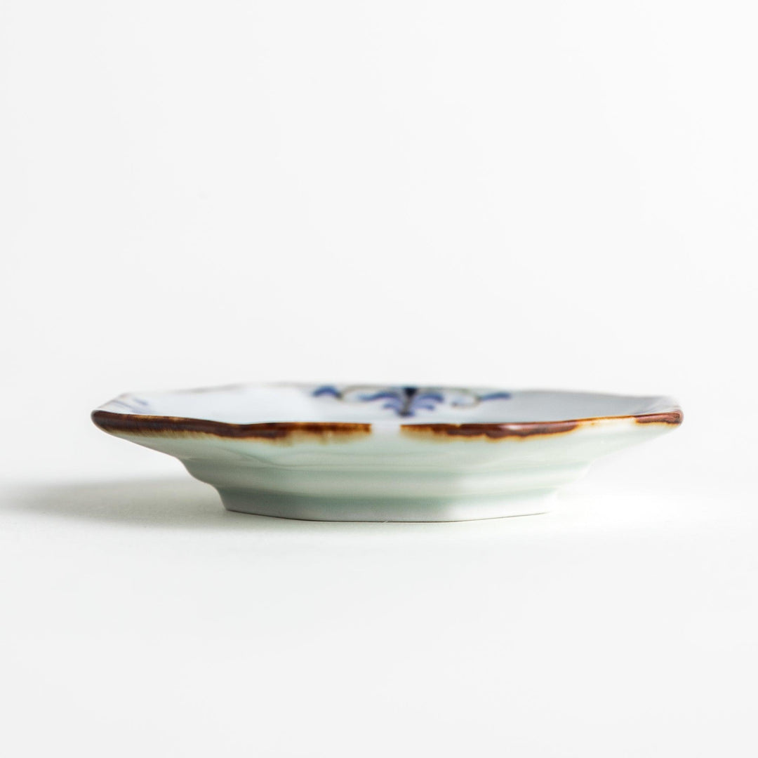 Octagonal white porcelain small sauce dish with a blue floral motif and brown accent trim.