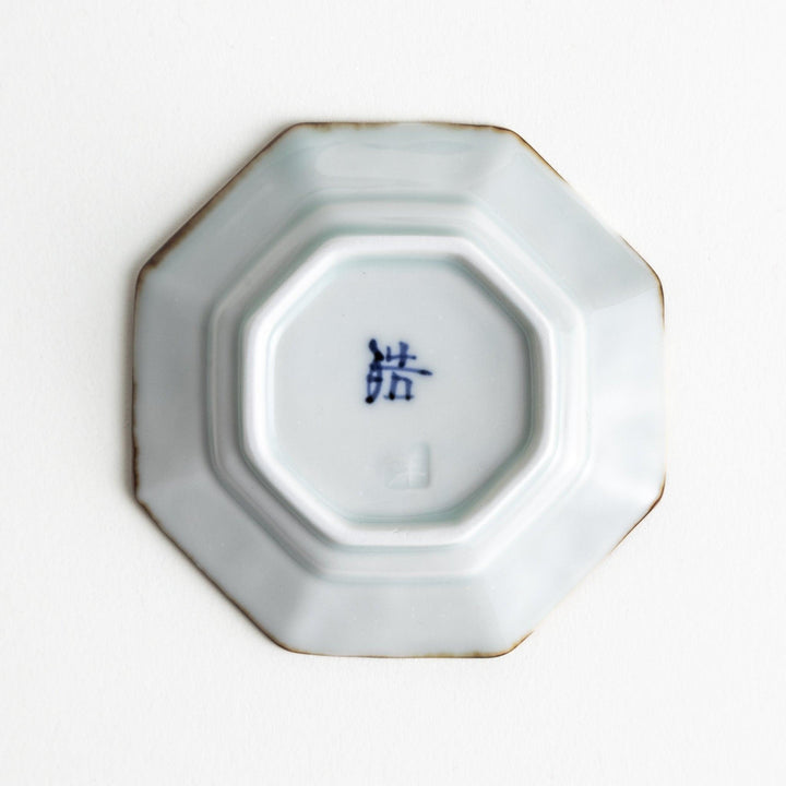Octagonal white porcelain small sauce dish with a blue floral motif and brown accent trim.
