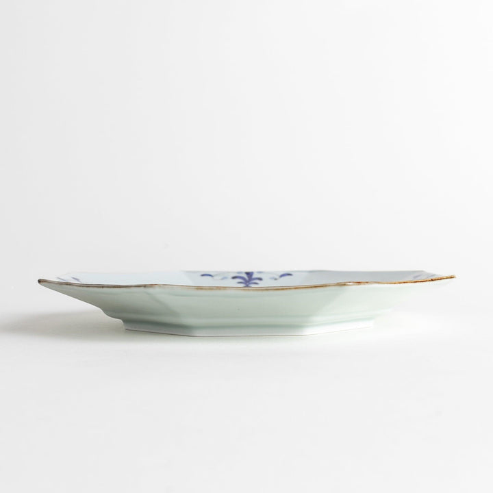 Octagonal white porcelain salad plate with a blue floral motif and brown accent trim.