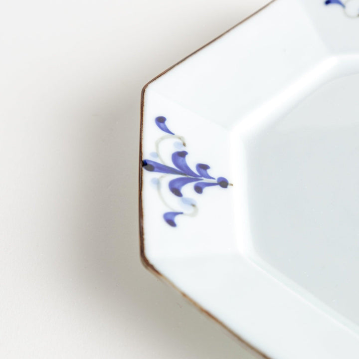 Octagonal white porcelain salad plate with a blue floral motif and brown accent trim.