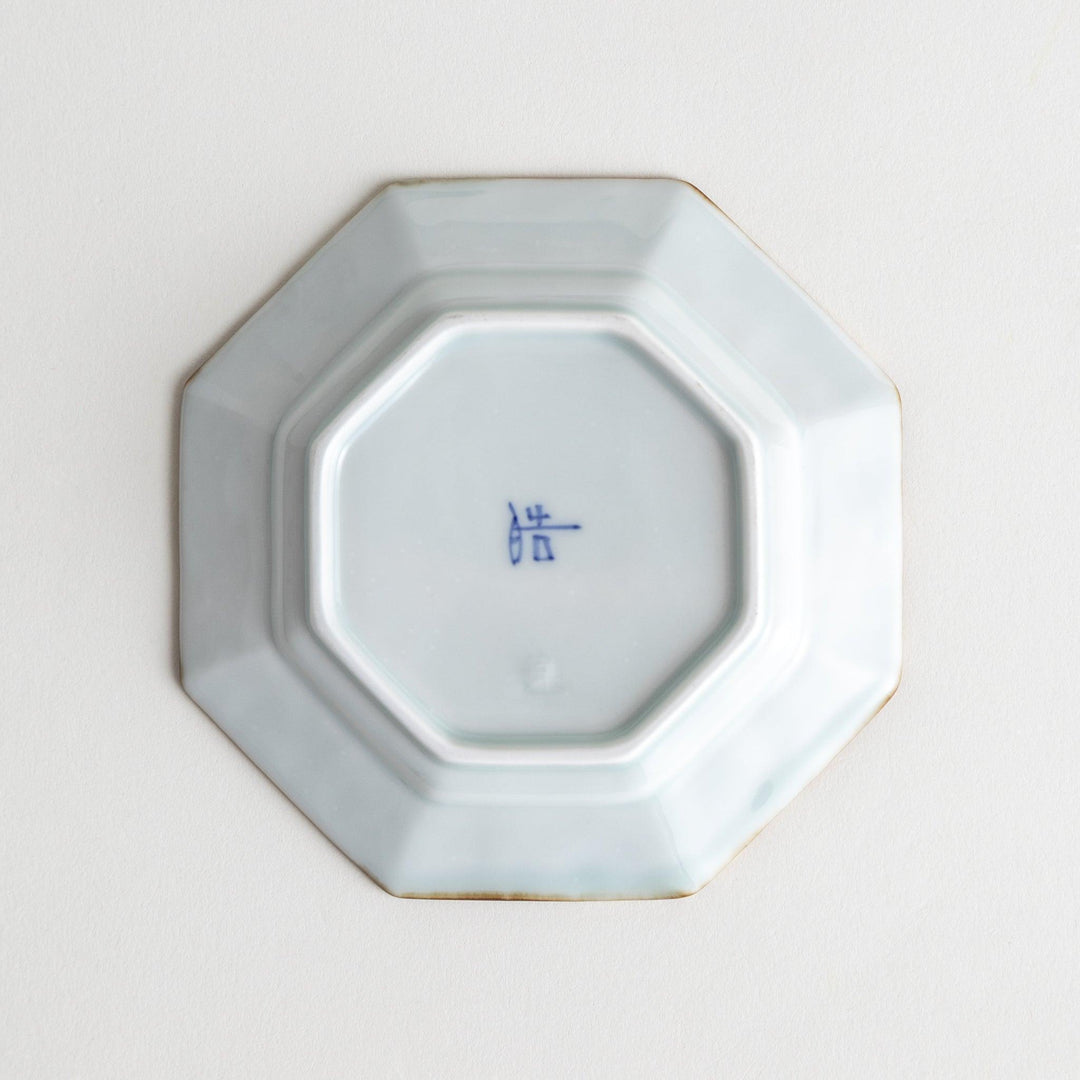 Octagonal white porcelain sauce dish with a blue floral motif and brown accent trim.