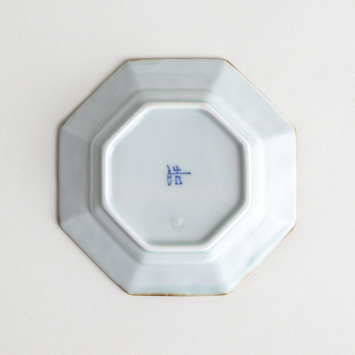Octagonal white porcelain sauce dish with a blue floral motif and brown accent trim.