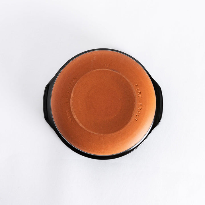 Underside of a brown donabe pot showing its unglazed ceramic base with a warm brown finish.