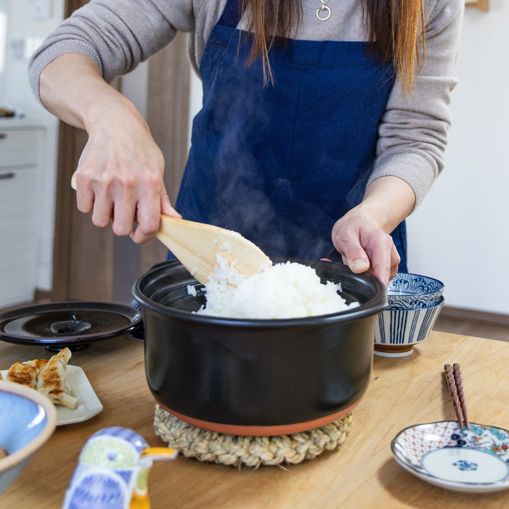 Nami from Just One Cookbook fluffing freshly cooked rice in navy Japanese donabe pot