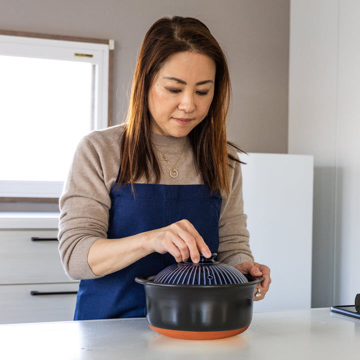 Nami from Just One Cookbook placing lid on navy Japanese donabe rice pot in kitchen