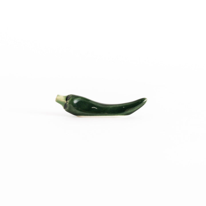 Side view of the green chili pepper chopsticks rest, capturing its curved design and vibrant green color.
