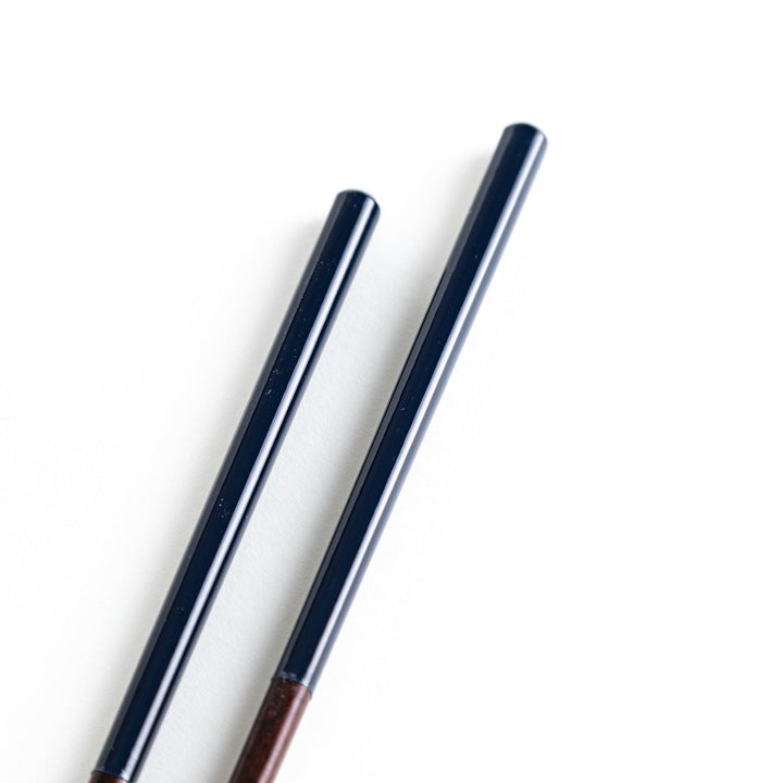 Chopsticks in different colors—white, yellow, olive green, navy blue, and dark brown—with wooden lower halves.