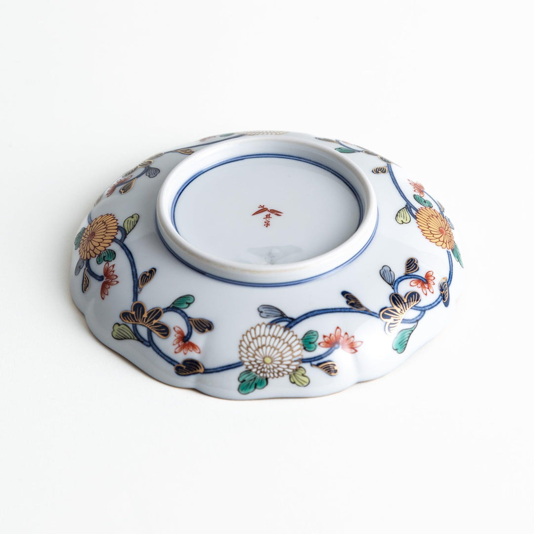 A deep round salad plate with a dark blue background, featuring a central floral design and intricate gold and red patterns with small scenes of Japanese landscapes.