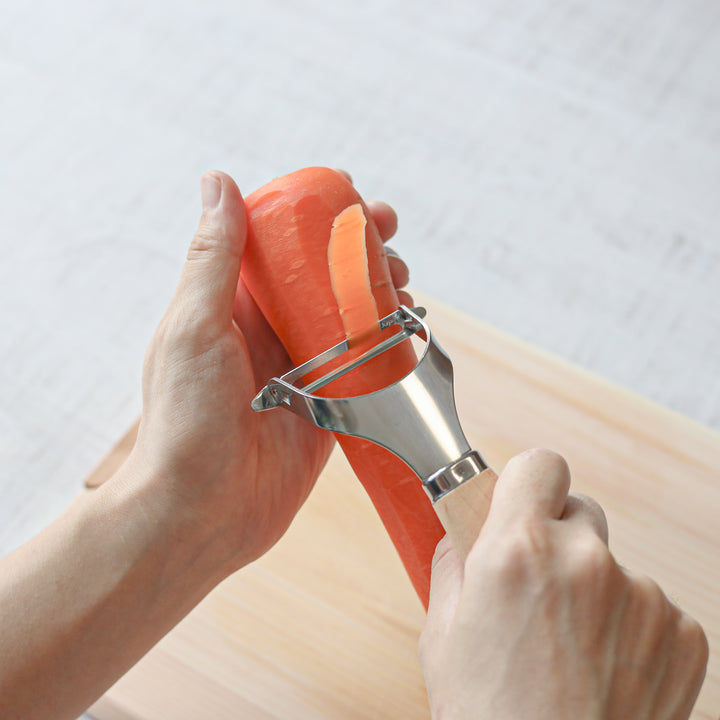 Japanese Wood Handle Peeler, a functional kitchenware with a stainless steel blade and ergonomic wooden handle, ideal for effortless vegetable peeling.