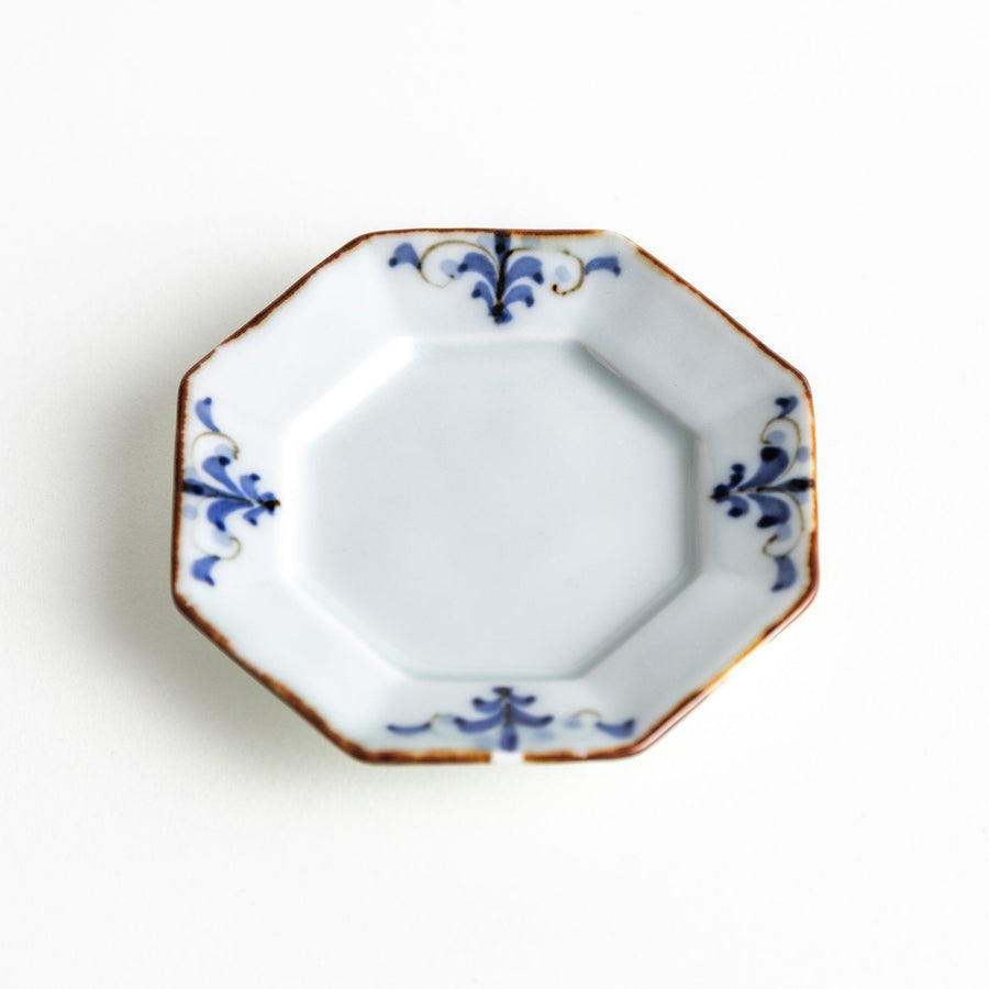 Octagonal white porcelain small sauce dish with a blue floral motif and brown accent trim.