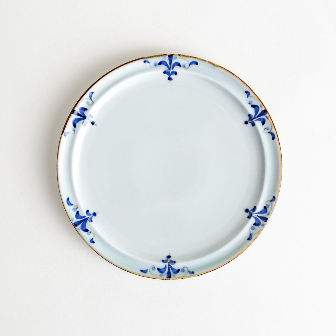 A small porcelain salad plate with a scalloped edge, decorated with blue and white floral motifs and brown accent trim.