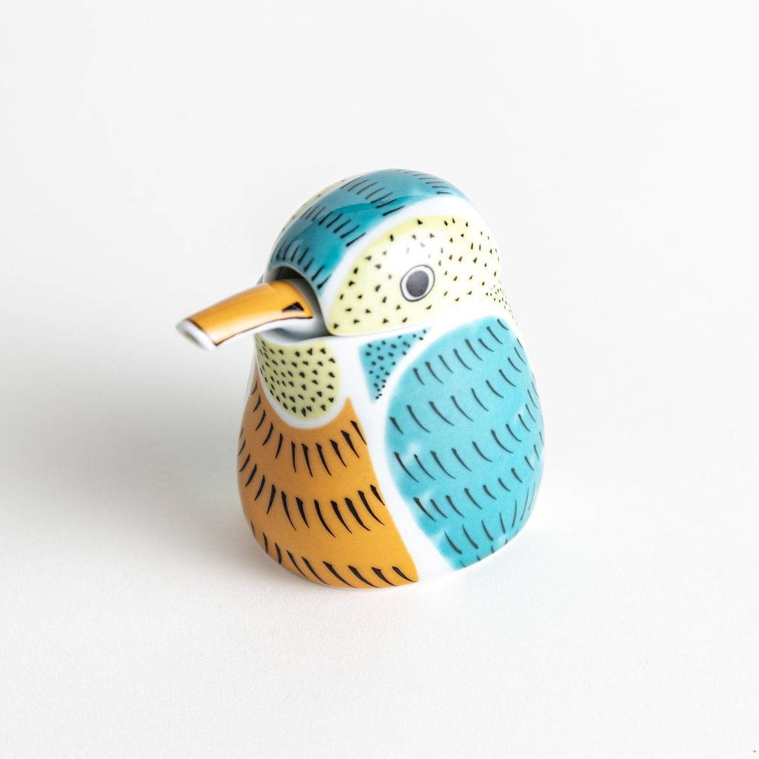 A bird-shaped ceramic soy sauce dispenser with vibrant patterns in turquoise, yellow, and green.
