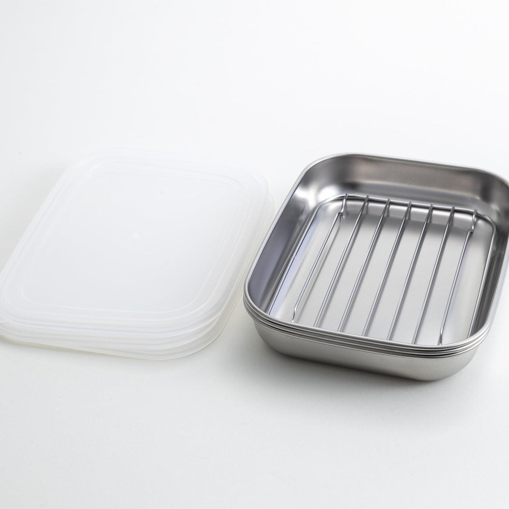Rectangular stainless steel food prep trays with a wire rack and a white plastic lid.