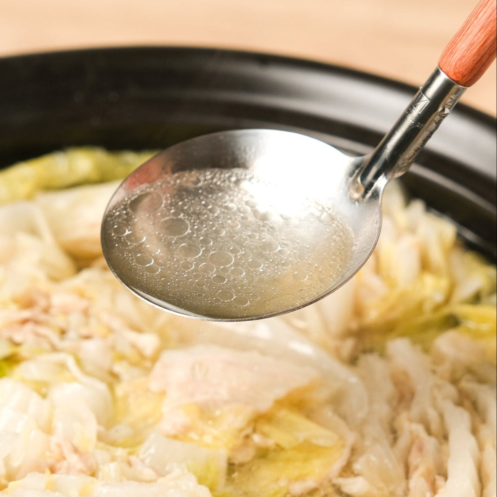 Scooping hot broth with the AUX Japanese Large Ladle, perfect for serving soups and stews directly from the pot with control.
