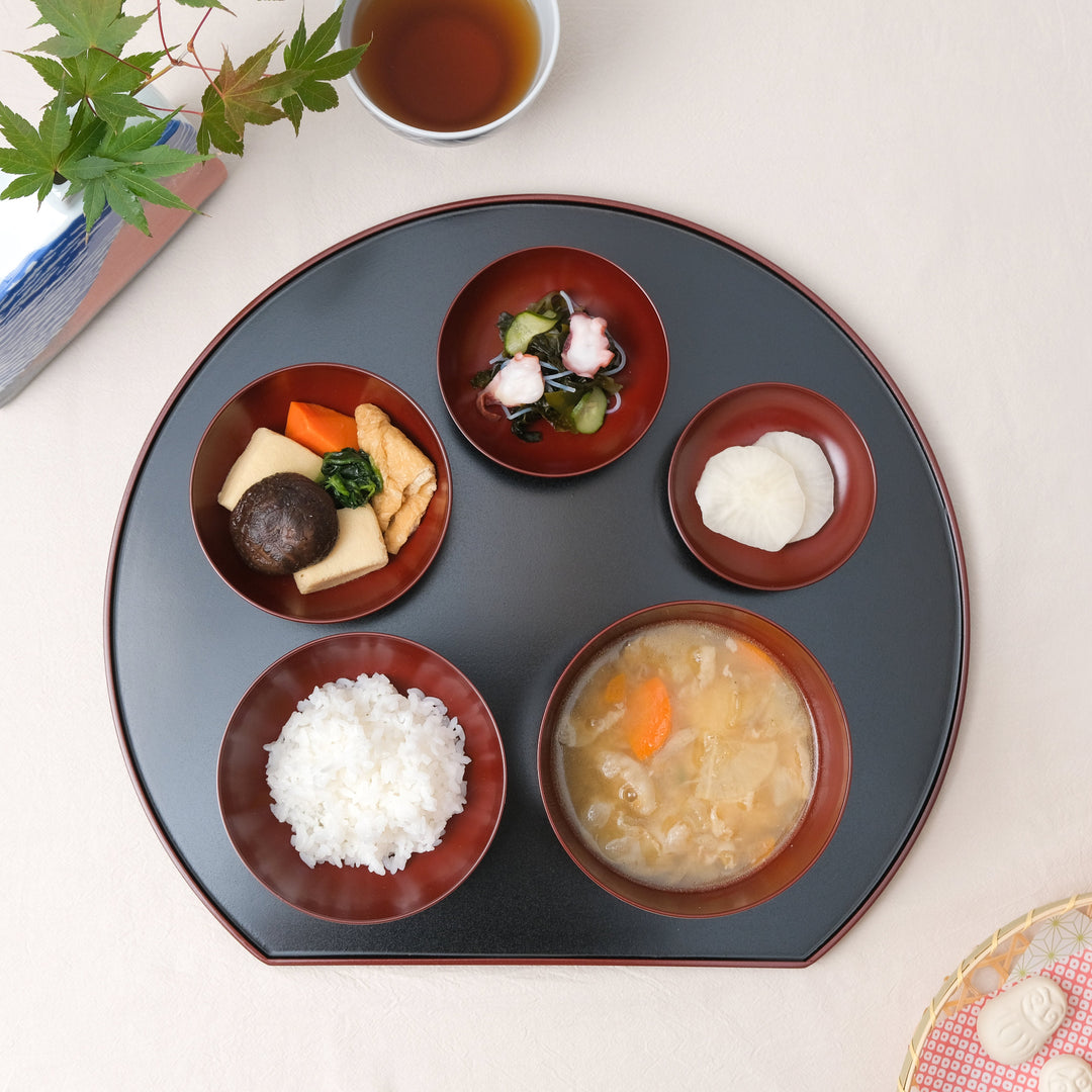 Traditional Japanese Oryoki bowl set with rice, miso soup, simmered vegetables, pickles, and octopus salad served on a black lacquered tray for mindful dining.