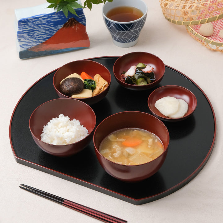 Japanese Oryoki bowl set with rice, miso soup, vegetables, pickles, and octopus salad on a black lacquered tray, served with chopsticks and tea for mindful dining.