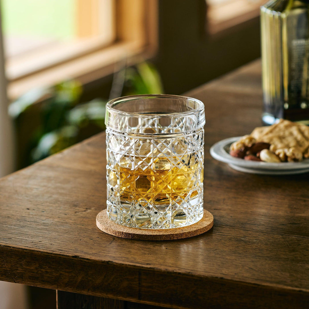 Cut Japanese whiskey glass with a lattice pattern, filled with whisky and ice, placed on a cork coaster.