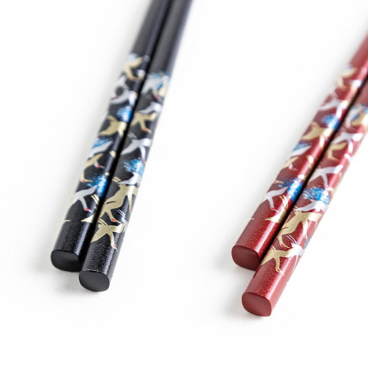 A boxed set of two pairs of chopsticks, one with a black and one with crane patterns on the handles.