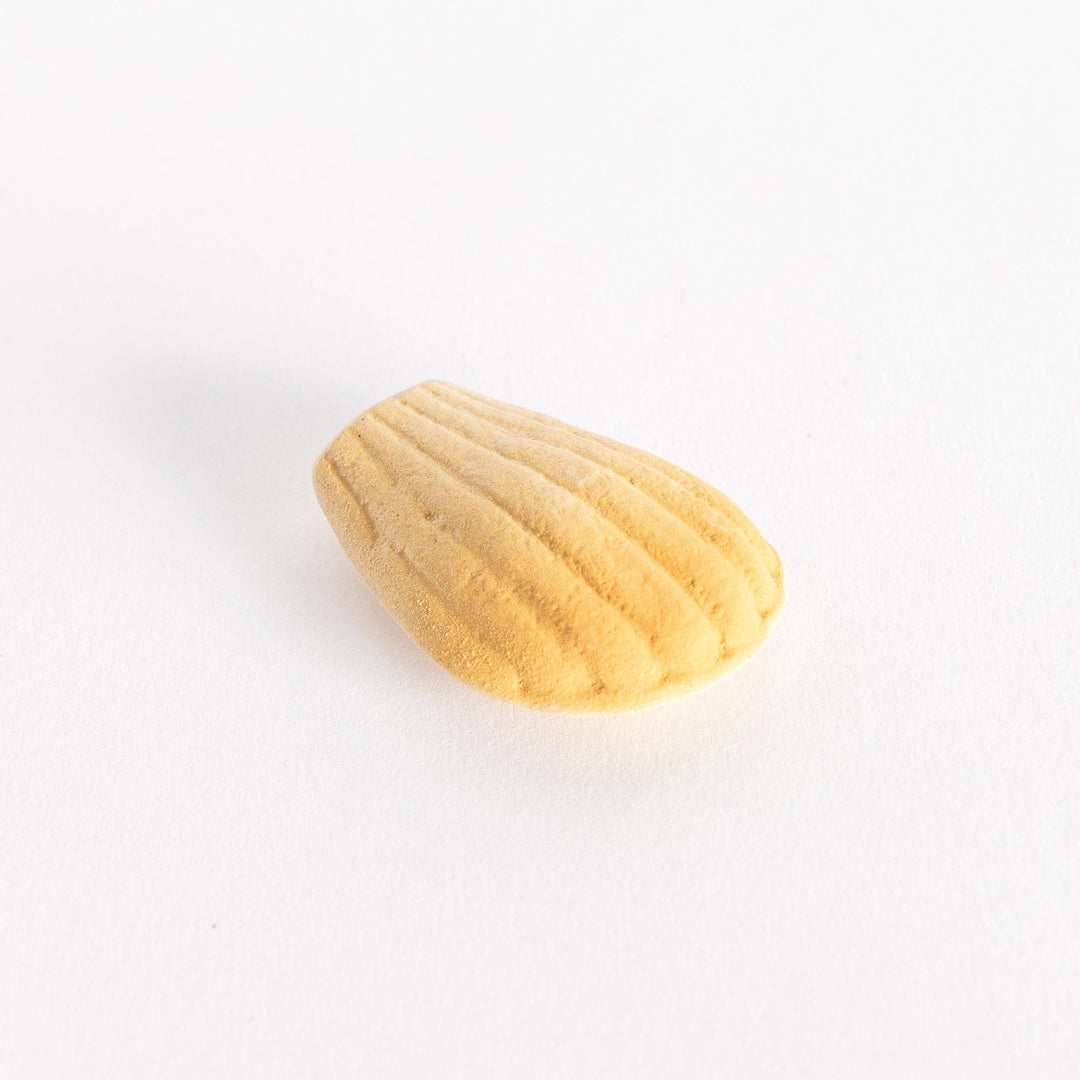 A slightly angled view of the ceramic golden madeleine chopstick rest, displaying its detailed ridges and rounded edges.