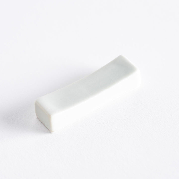 Minimalist white porcelain chopstick holder displayed alone on a clean white surface.