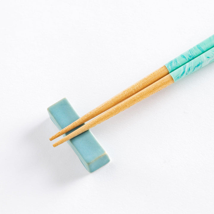 Close-up of the aqua chopsticks, highlighting the unique marbled pattern on the handles with wooden tips.