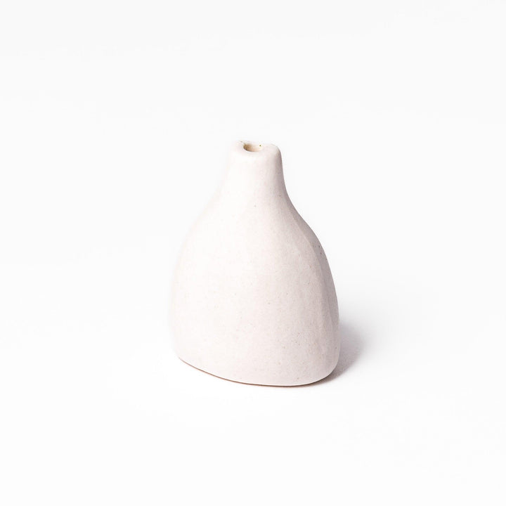 Minimalist white ceramic bud vase with a teardrop shape and narrow opening, ideal for showcasing a single flower in a serene, modern setting.