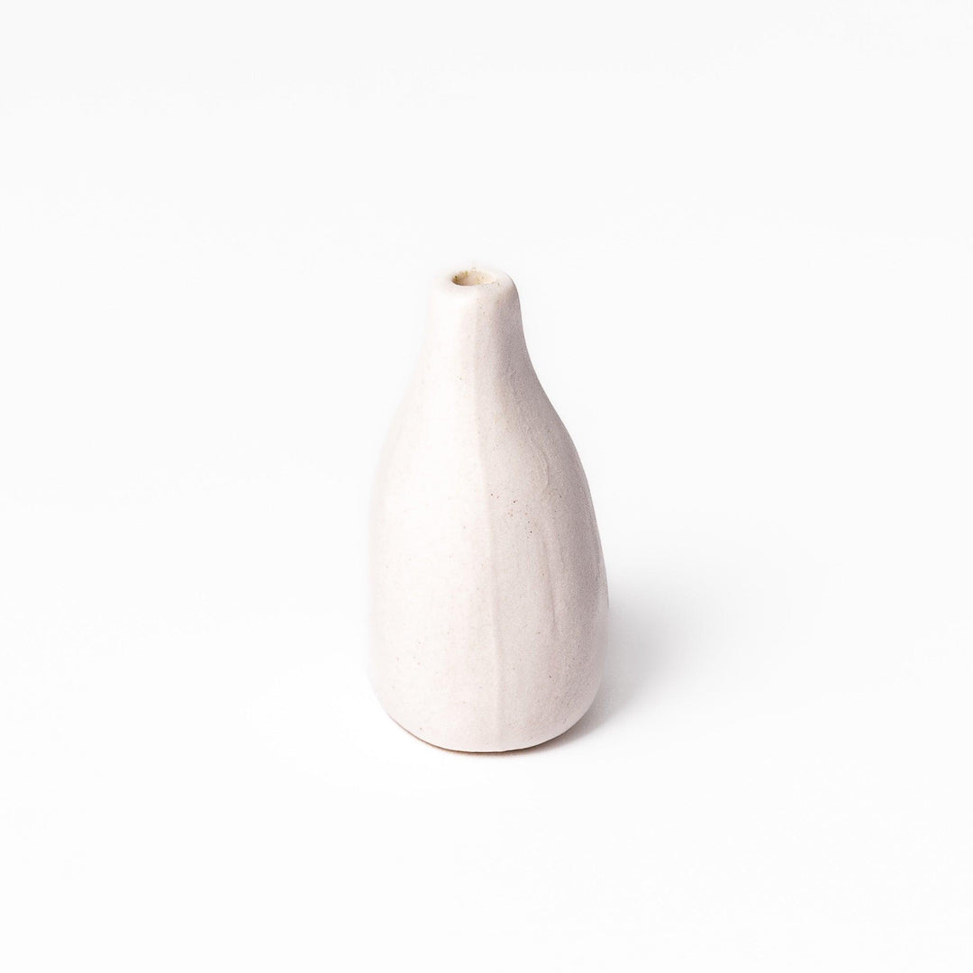 Minimalist white ceramic bud vase with a teardrop shape and narrow opening, ideal for showcasing a single flower in a serene, modern setting.