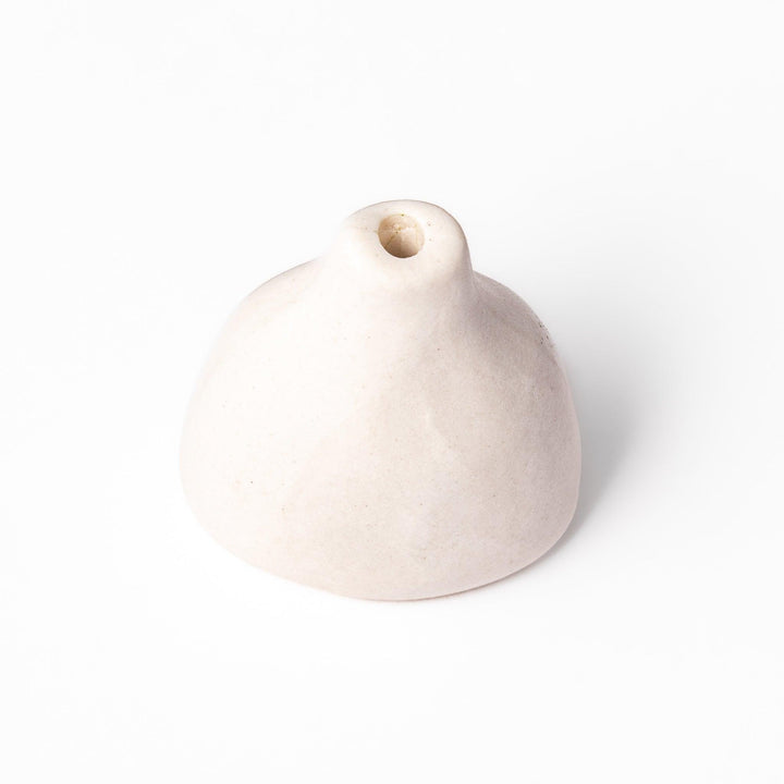 Minimalist white ceramic bud vase with a teardrop shape and narrow opening, ideal for showcasing a single flower in a serene, modern setting.