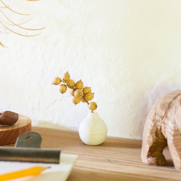Minimalist white ceramic bud vase with an orb-like shape and subtle center ridge, ideal for adding soft, sculptural charm to any small floral display.