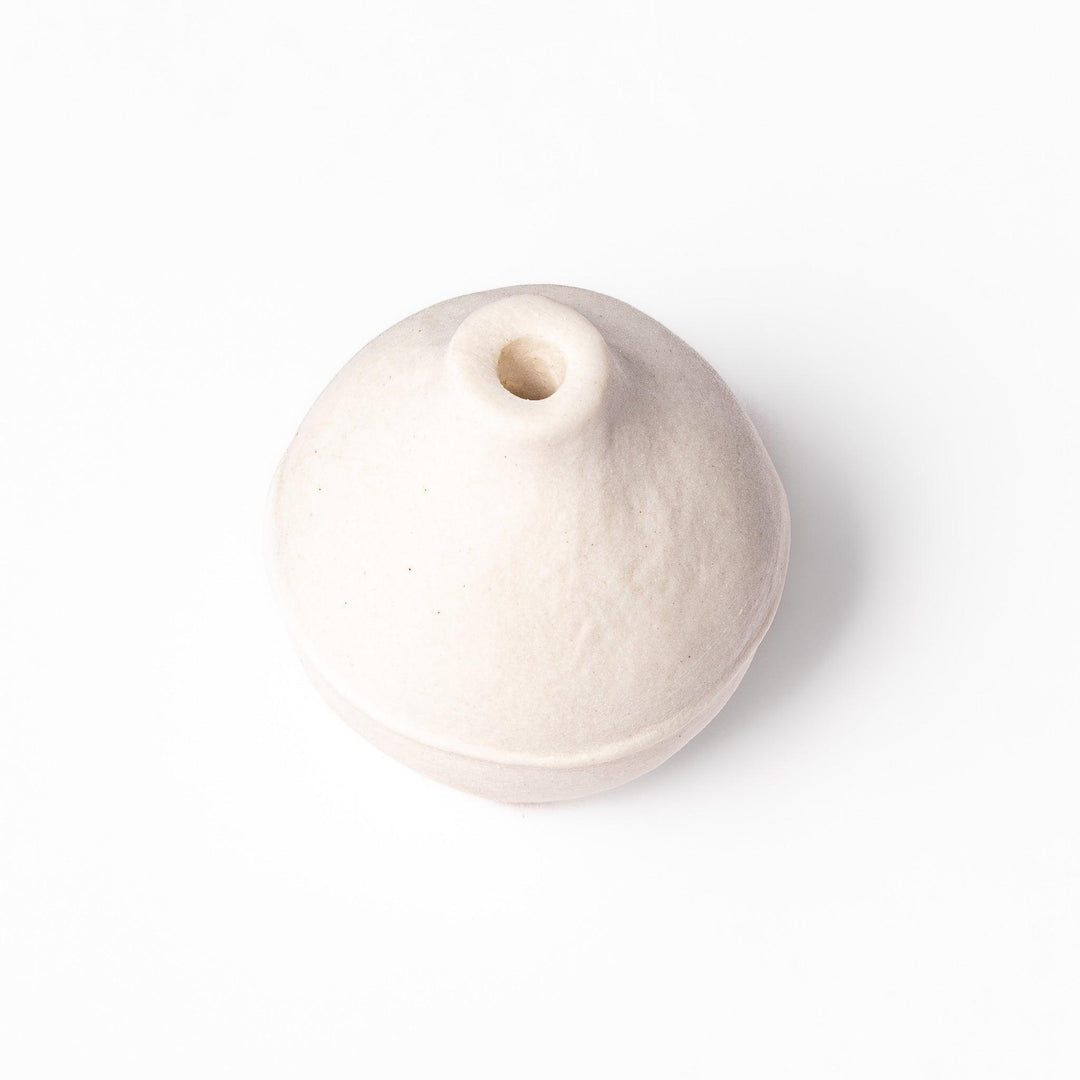 Minimalist white ceramic bud vase with an orb-like shape and subtle center ridge, ideal for adding soft, sculptural charm to any small floral display.