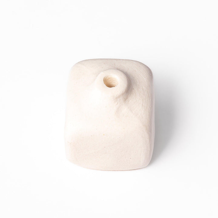 Minimalist white ceramic bud vase with a rounded square shape and narrow opening, perfect for adding subtle elegance to small floral arrangements.