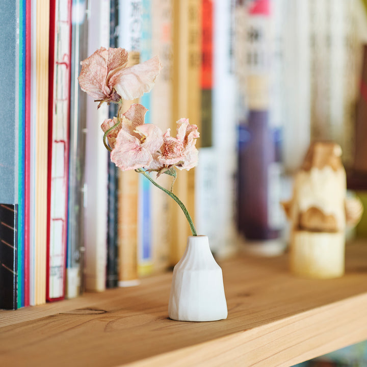 Minimalist white ceramic bud vase with a faceted prism shape and narrow neck, offering a modern geometric touch for single stems or dried flowers.