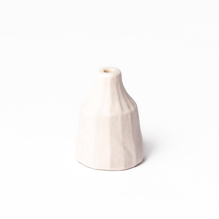 Minimalist white ceramic bud vase with a faceted prism shape and narrow neck, offering a modern geometric touch for single stems or dried flowers.