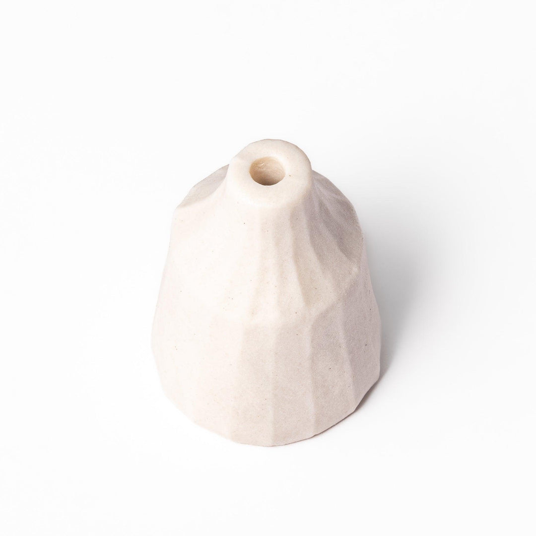 Minimalist white ceramic bud vase with a faceted prism shape and narrow neck, offering a modern geometric touch for single stems or dried flowers.