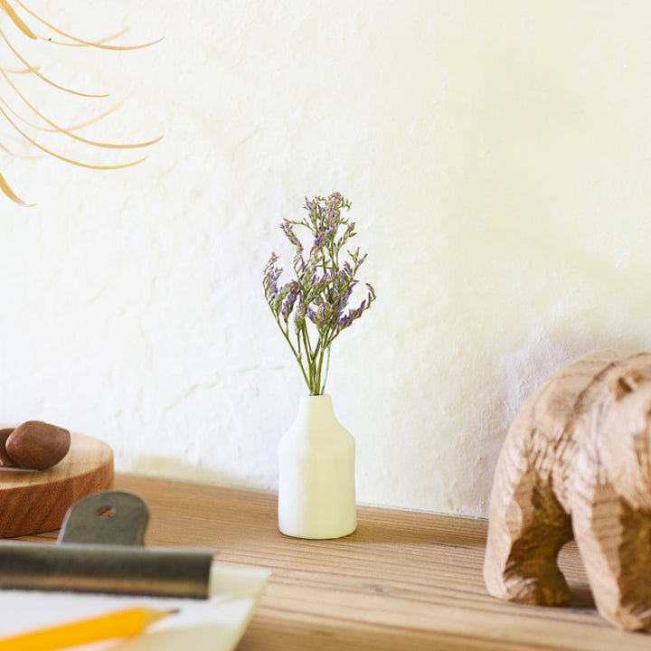 Minimalist white ceramic bud vase with a cylindrical body and narrow neck, perfect for single stems and adding clean, modern charm to any space.