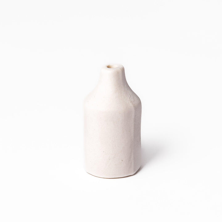 Minimalist white ceramic bud vase with a cylindrical body and narrow neck, perfect for single stems and adding clean, modern charm to any space.