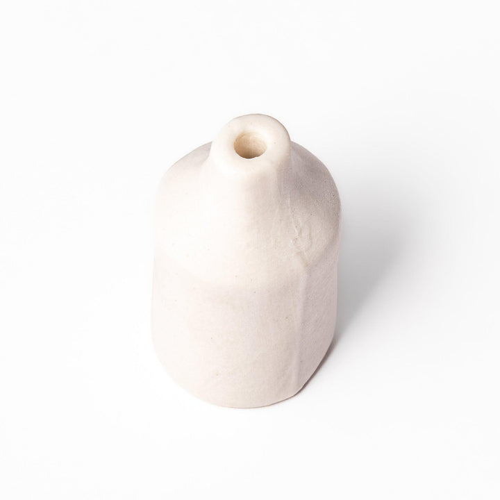 Minimalist white ceramic bud vase with a cylindrical body and narrow neck, perfect for single stems and adding clean, modern charm to any space.