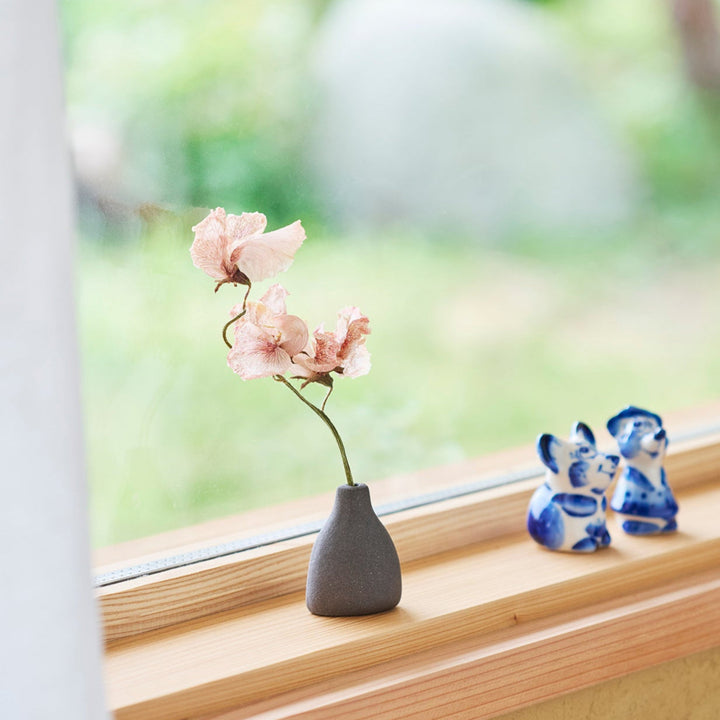 Minimalist dark ceramic bud vase with a teardrop silhouette and textured surface, perfect for adding earthy elegance to floral or dried arrangements.