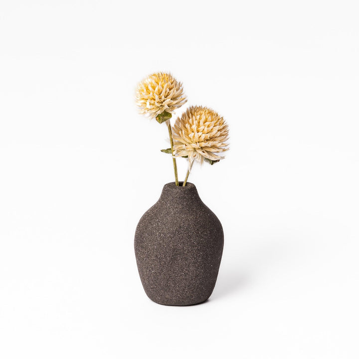 Minimalist dark ceramic bud vase with a pear-shaped form and textured finish, ideal for adding warmth and organic charm to floral displays.