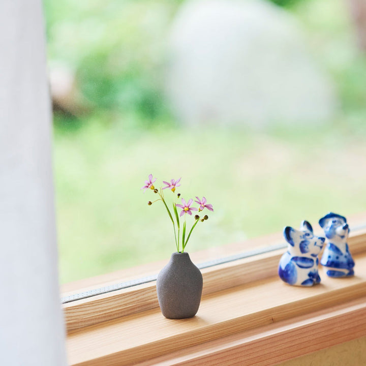 Minimalist dark ceramic bud vase with a pear-shaped form and textured finish, ideal for adding warmth and organic charm to floral displays.