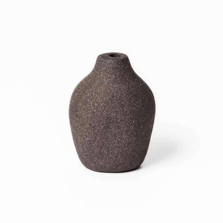 Minimalist dark ceramic bud vase with a pear-shaped form and textured finish, ideal for adding warmth and organic charm to floral displays.