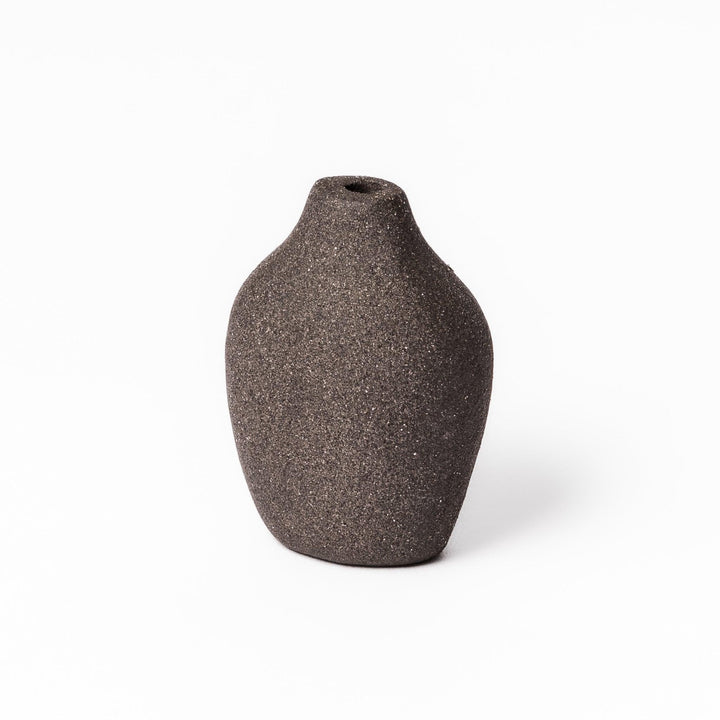 Minimalist dark ceramic bud vase with a pear-shaped form and textured finish, ideal for adding warmth and organic charm to floral displays.