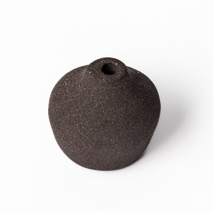 Minimalist dark ceramic bud vase with a pear-shaped form and textured finish, ideal for adding warmth and organic charm to floral displays.